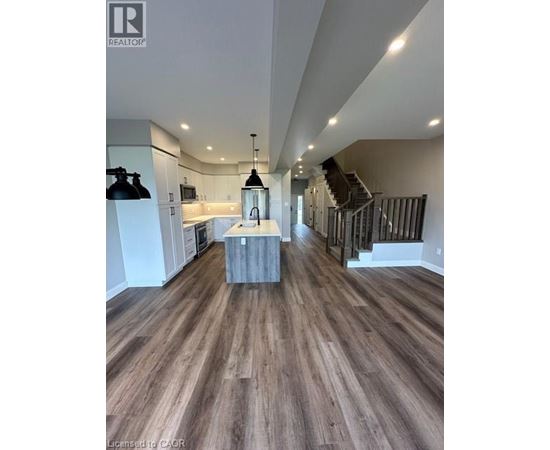A spacious room with wooden flooring and a staircase.
