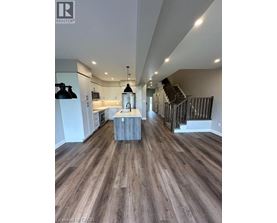 A spacious room with wooden flooring and a staircase.