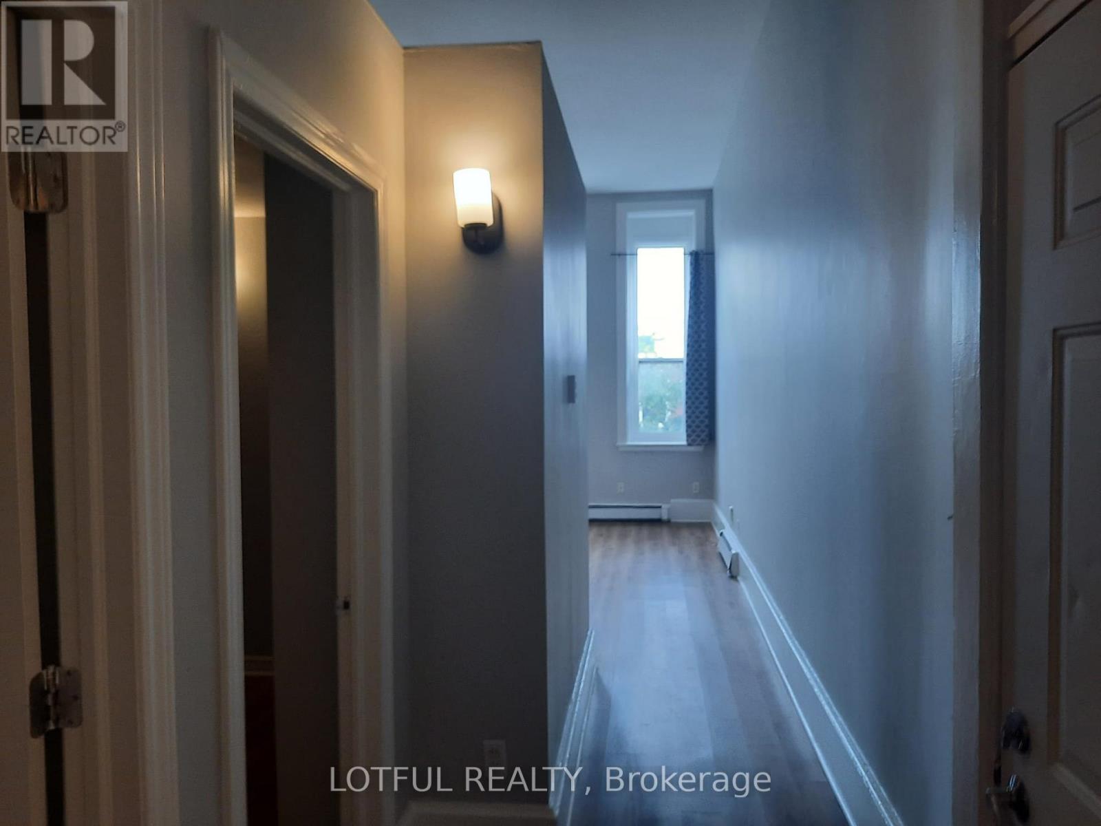 A hallway with a door on the left and a window on the right.