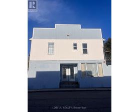 A white building with a blue roof and a sign that says Lotful Realty, Brokerage.