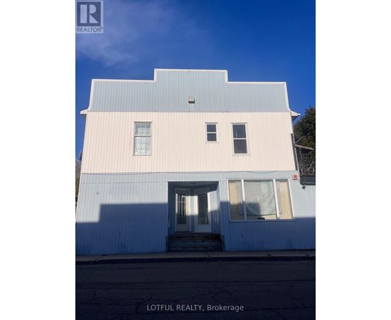 A white building with a blue roof and a sign that says Lotful Realty, Brokerage.