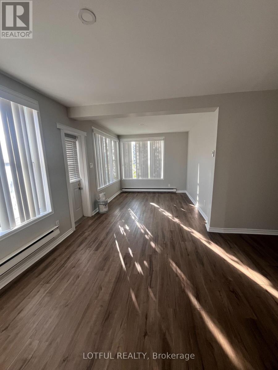 A sunlit room with wooden floors and white walls.