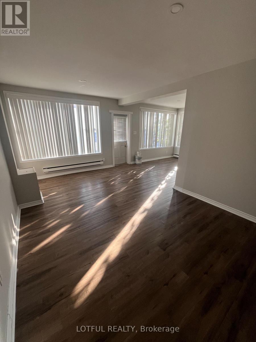 A spacious room with wooden floors and large windows.