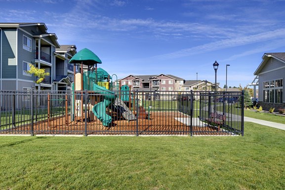 Playground with grass by apt buildings Copper Trail Apartments | Apartments for rent in Olympia, WA 
