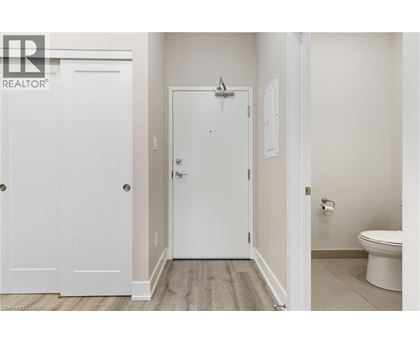 A white door in a room with a toilet in the background.