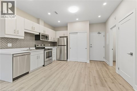 A kitchen with white cabinets and a wooden floor.
