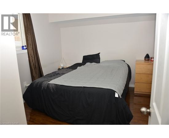 A bedroom with a bed, nightstand, and a lamp.