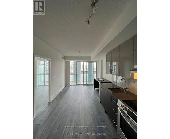 A modern kitchen with dark wood floors and stainless steel appliances.