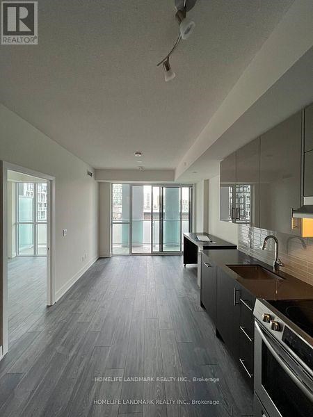 A modern kitchen with dark wood floors and stainless steel appliances.