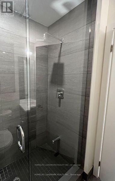A bathroom with a glass shower stall and a toilet.