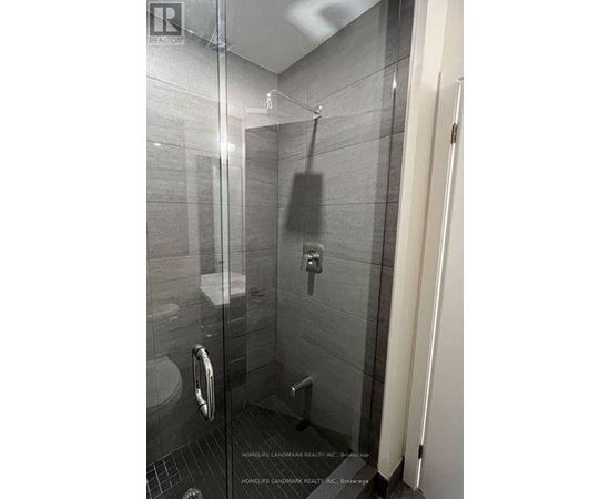 A bathroom with a glass shower stall and a toilet.