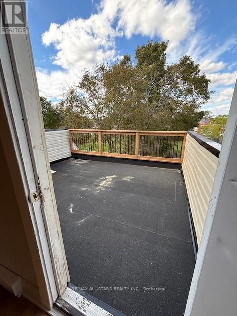 A balcony with a wooden railing and a view of trees.
