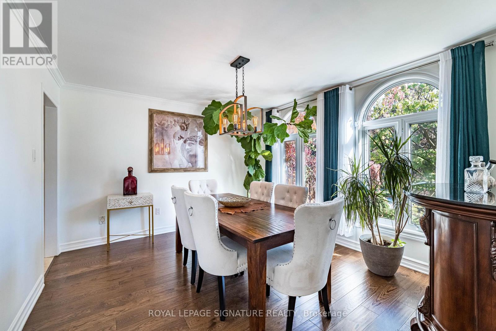 A dining room with a wooden table and white chairs.