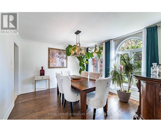 A dining room with a wooden table and white chairs.