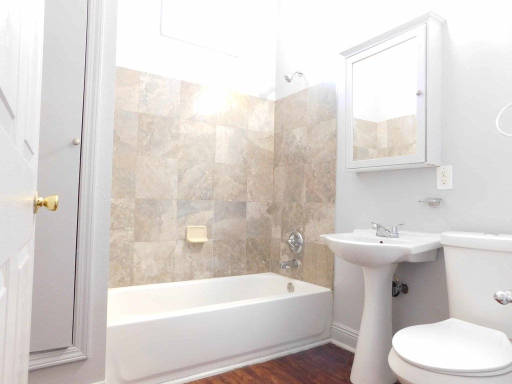 A white bathroom with a tub, sink, and toilet.