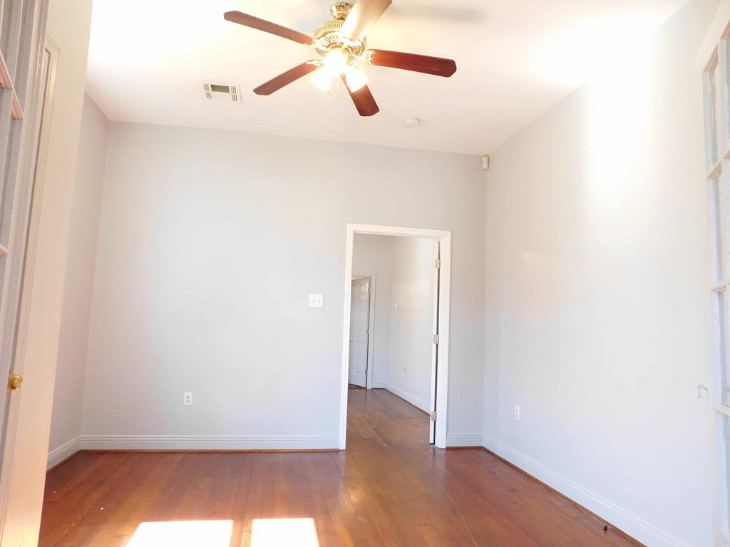 A room with a ceiling fan and wooden floors.