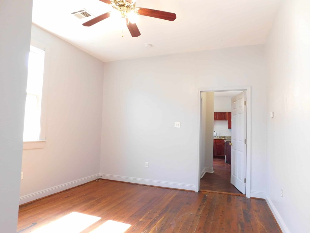 A room with a ceiling fan and wooden floors.