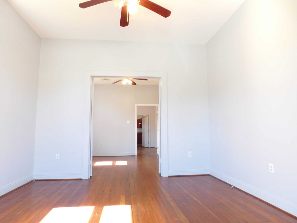 A room with a ceiling fan and a doorway leading to another room.