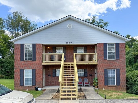 A two-story brick house with a wooden staircase leading to the second floor.