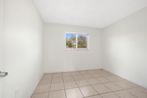 A room with a window showing a view of trees and sky.