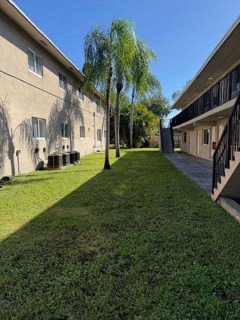 A tree in the middle of a grassy area between two buildings.