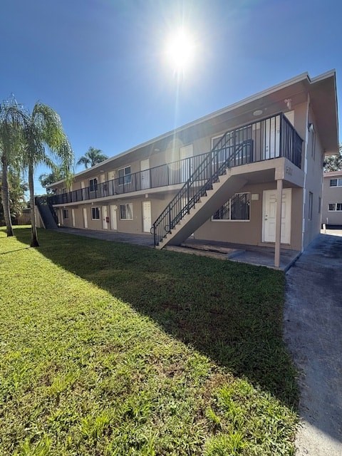 A sunny day at a two-story apartment building with a staircase leading to the second floor.