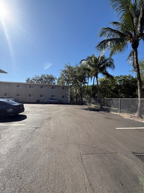 A sunny day at the parking lot with palm trees and a building in the background.