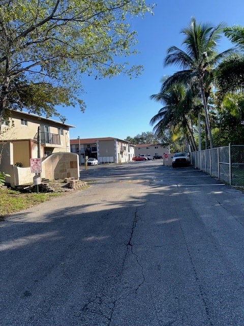 A street view of a residential area with houses and palm trees.