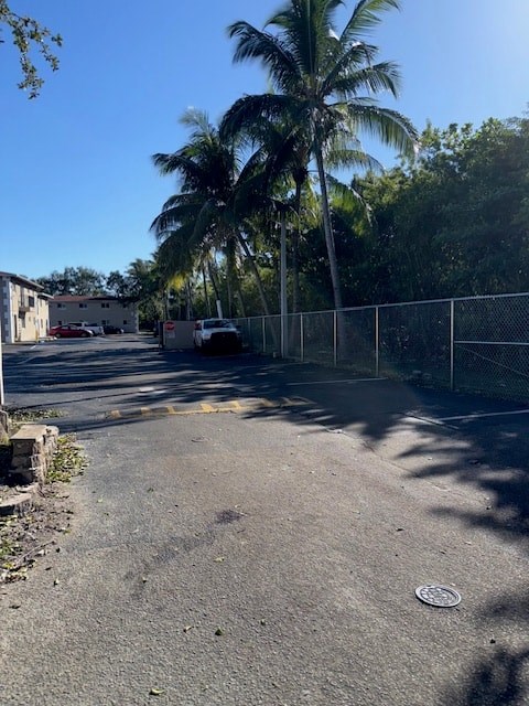 A street with a fence and palm trees.