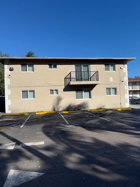 A beige apartment building with a black balcony on the second floor.