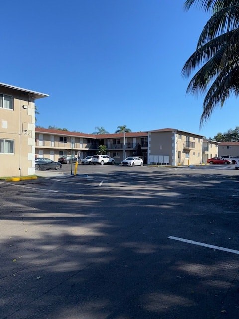 A parking lot with a few cars and apartment buildings in the background.