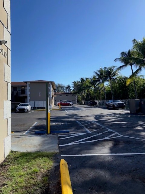 A parking lot with a yellow pole in the foreground and a building with the number 610 on it.