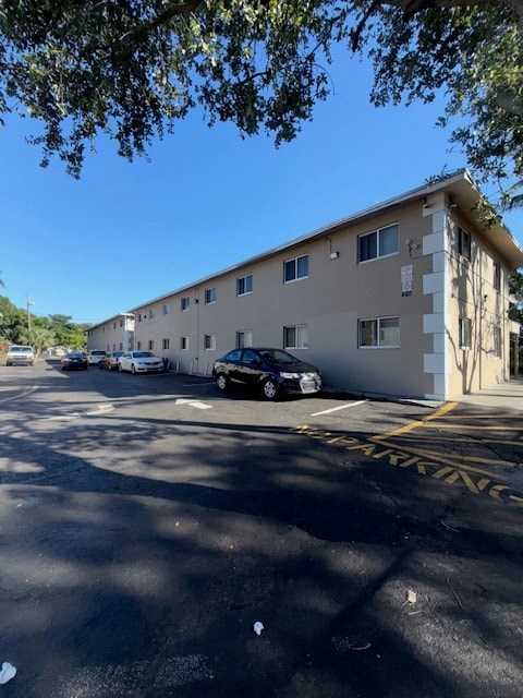 A parking lot in front of a building with cars parked.