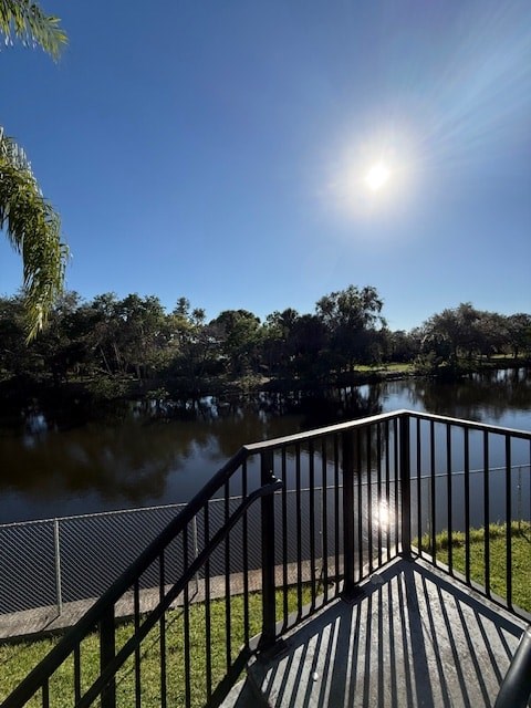 A sunny day at the lake with a fence and trees in the background.