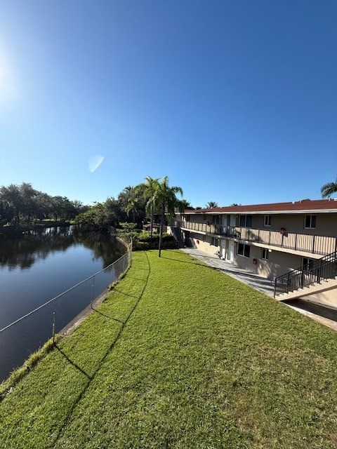A sunny day at a park with a building and a body of water.