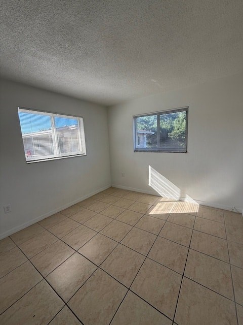 A room with tiled flooring and two windows.