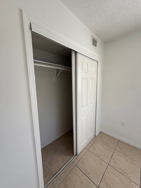A white door is open to a small, empty room with tiled flooring.