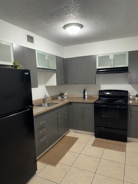 A black refrigerator is in a kitchen with black appliances.