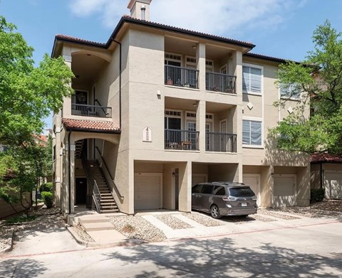 A two-story apartment building with a car parked in front.