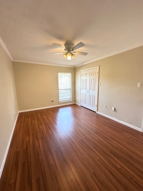 A room with a ceiling fan and wooden flooring.