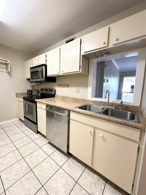 A kitchen with white cabinets and a tiled floor.