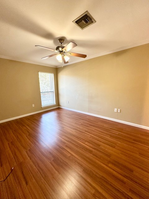 A room with a ceiling fan and wooden flooring.