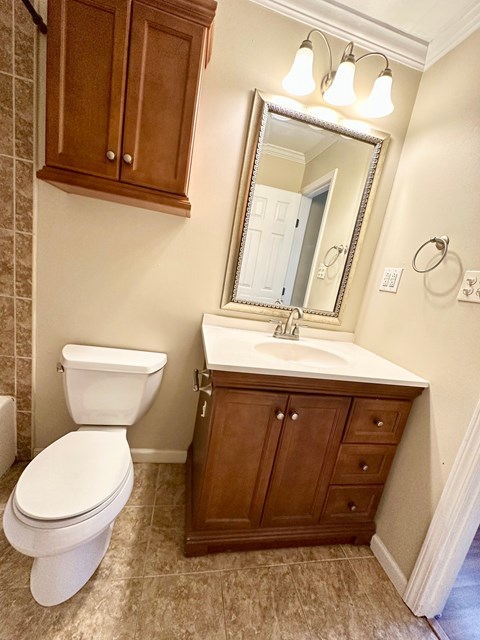 A bathroom with a toilet, sink, and mirror.