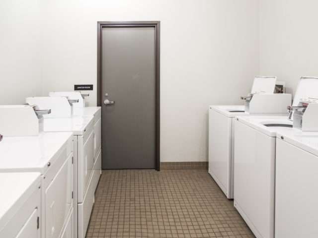 A bathroom with a brown door and white sinks.