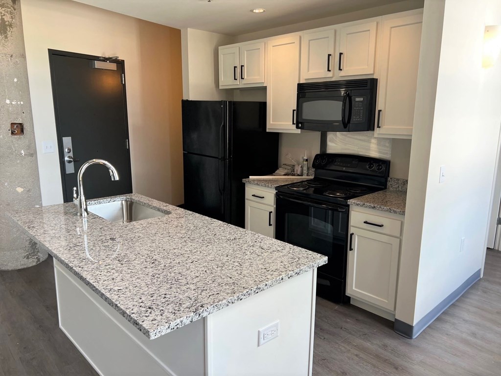 A kitchen with black appliances and granite countertops.