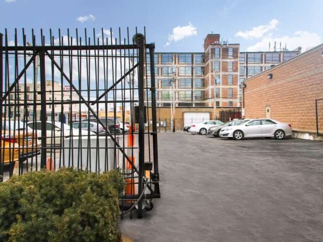 A parking lot with cars and a metal gate.