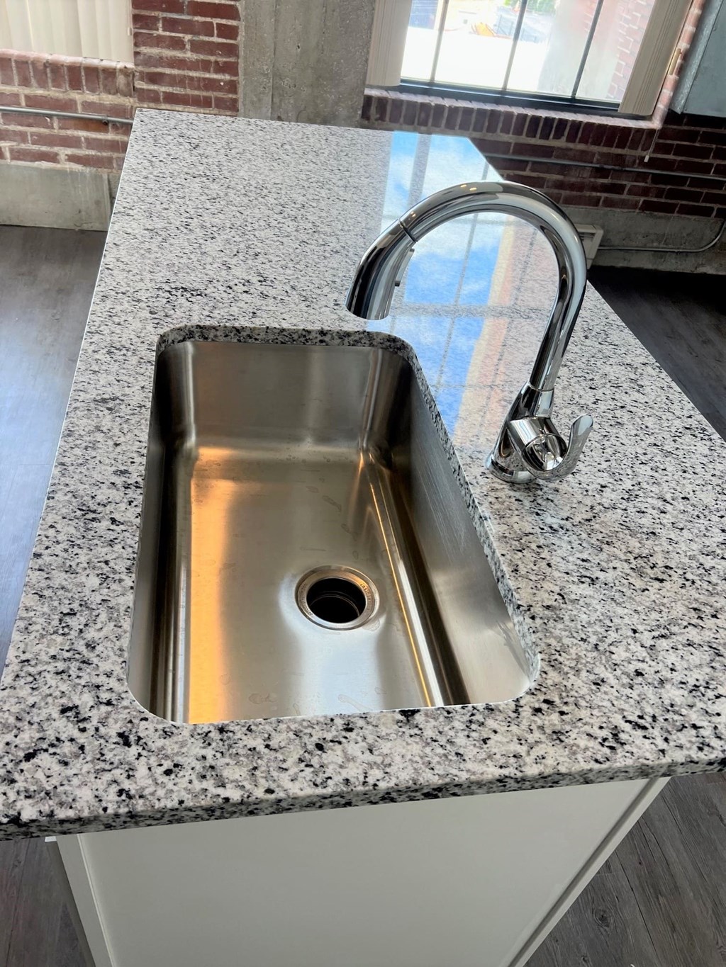 A stainless steel sink with a chrome faucet is installed in a granite countertop.