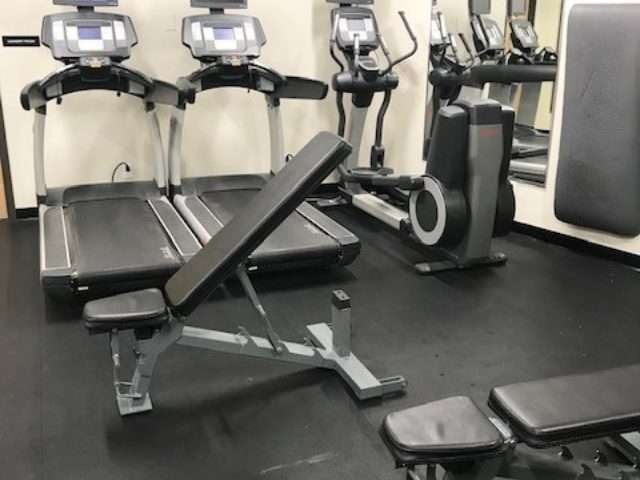 A treadmill and a stationary bike are in a gym.