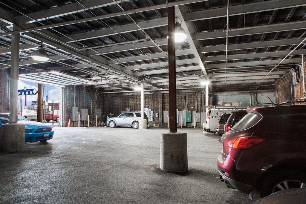 A parking garage with a few cars and concrete pillars.