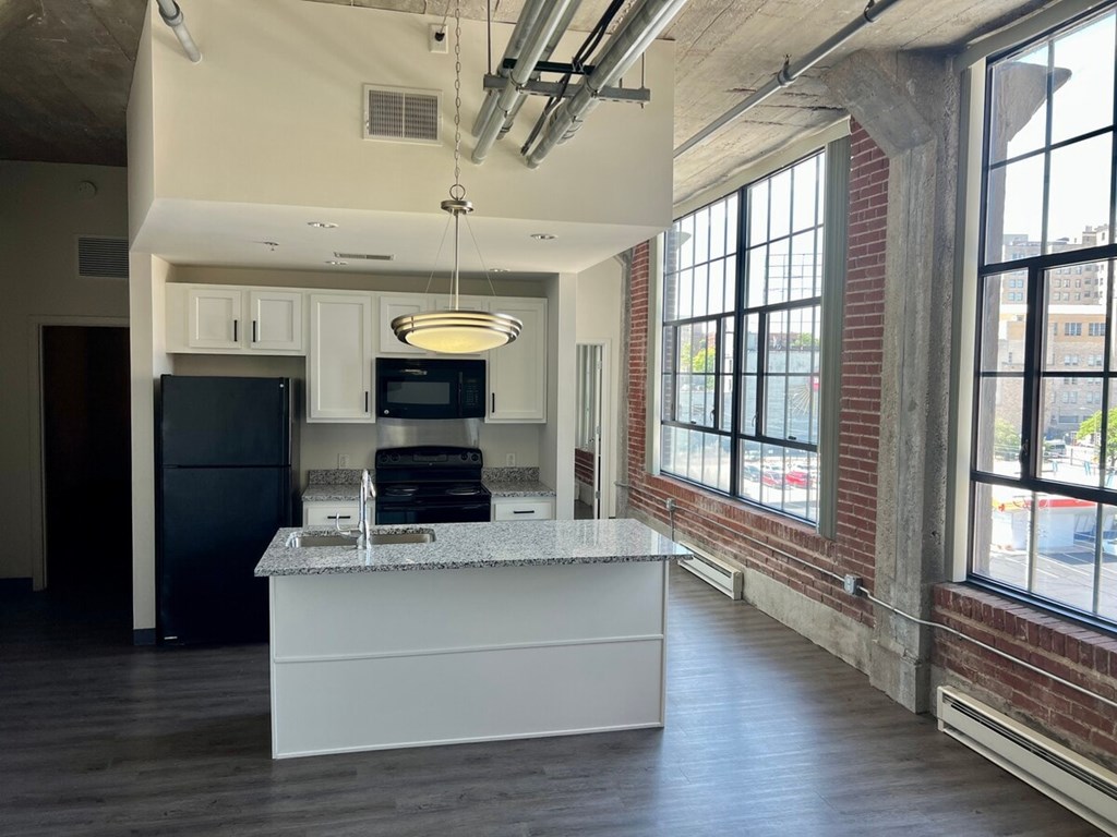 A kitchen with a granite countertop and a black refrigerator.